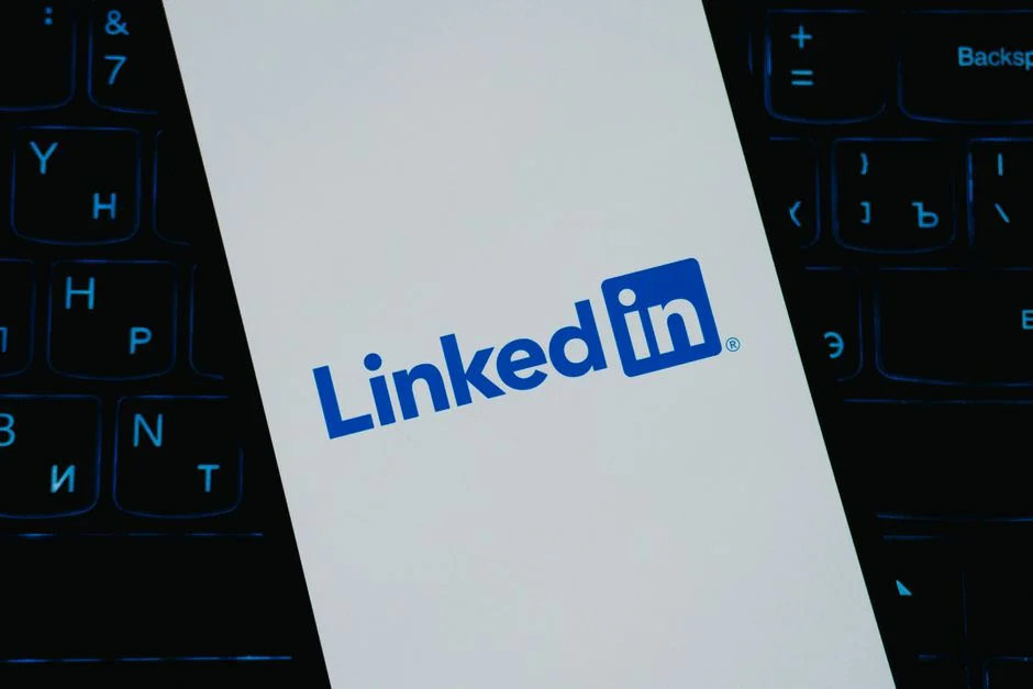 A person indoors analyzes stock data using a smartphone and a laptop.